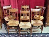 four wooden chairs are lined up on a rug in front of a red curtain