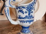 a blue and white pitcher sitting on a table with a plate