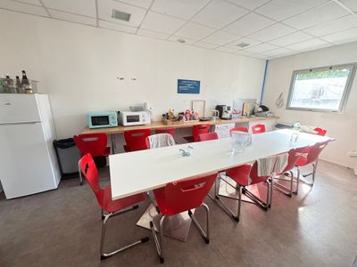 des tables et des chaises dans une pièce équipée d'un réfrigérateur et d'un micro-ondes
