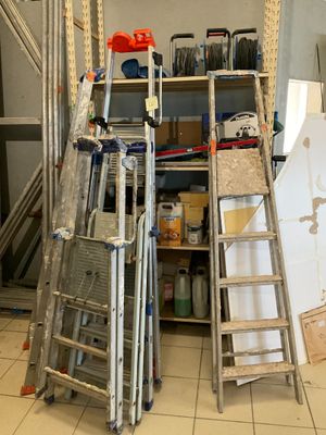 Plusieurs échelles sont empilées les unes sur les autres dans une pièce.