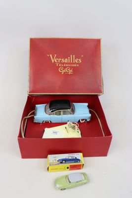 une petite voiture bleue dans une boîte rouge à côté d'une paire de ciseaux