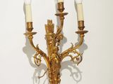 an image of a golden wall light with three candles on it