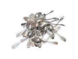 une pile de cuillères et de fourchettes en argent posées sur une surface blanche