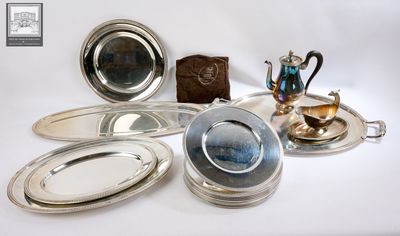 a lot of silver plates and trays sitting on a table