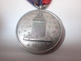 silver medal with a red, white, and blue ribbon around it
