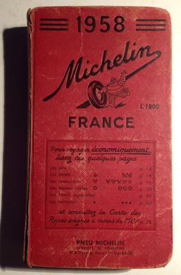 un vieux livre rouge posé sur une table à côté d'une table blanche