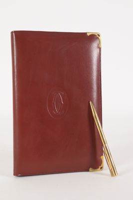 un carnet en cuir marron sur lequel est posé un stylo