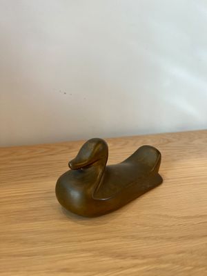 une petite statue représentant un canard posé sur une table en bois