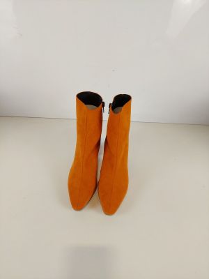 une paire de bottes orange posée sur une table blanche