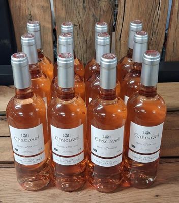 Six bouteilles de vin rosé sont alignées sur une table en bois
