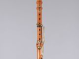 an orange and black clarinet on a clear stand