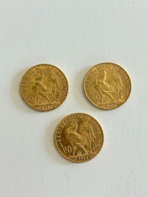 three gold sovereigns on a white surface