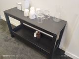 une table noire avec une étagère et des tasses posées dessus