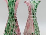 pair of pink and green glass vases sitting on a white surface