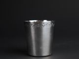 a close up of a silver cup on a black surface