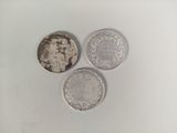 three silver coins sitting on top of each other on a white surface