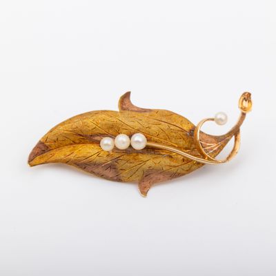 une image représentant une broche ornée de deux perles sur une feuille