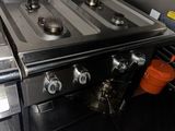 plaque de cuisson en acier inoxydable à deux feux, avec une casserole posée sur le côté