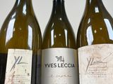 three bottles of wine are lined up on a white surface