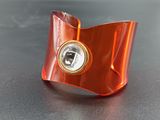 an orange bracelet with a diamond in the center on a black surface