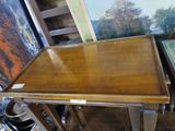 a wooden table that has a painting on the wall behind it