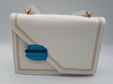 le petit sac à main blanc rehaussé de touches de bleu est posé sur une surface blanche