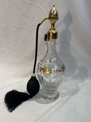 une bouteille en verre munie d'une poignée noire et d'un pompon