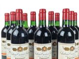 six bottles of red wine lined up in a row on a white surface