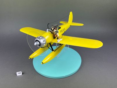 maquette d'avion jaune avec un pilote assis dessus, posée sur un socle bleu