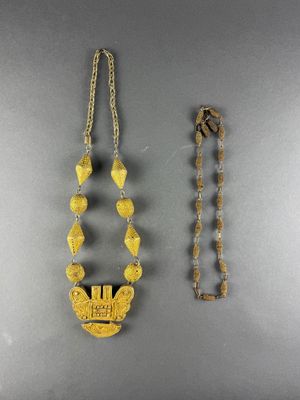 two pieces of jewelry are displayed on a gray surface