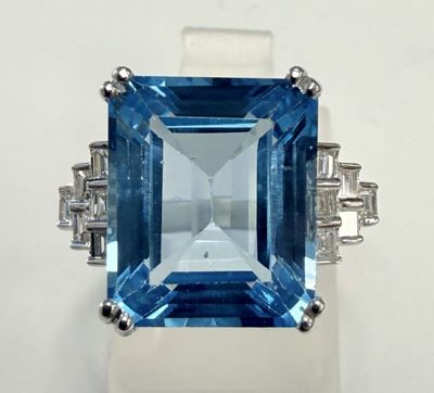 une photo d'une bague en topaze bleue et diamants posée sur une surface blanche