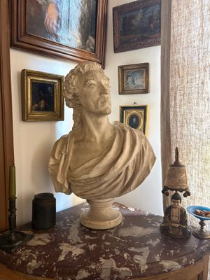 a bust of a man sitting on a table in front of a window