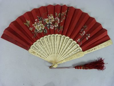 une image représentant un éventail rouge orné de fleurs et d'un pompon