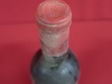 a small glass bottle with a red lid on a red surface