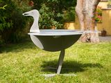 a duck that is sitting on a grill in the grass