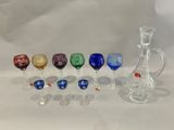 sur la table, de nombreux verres à vin de différentes couleurs et une carafe