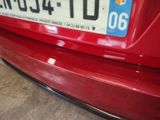 the rear end of a red car with a license plate on it