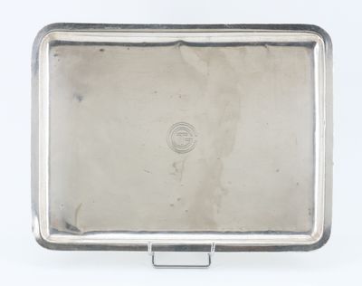 une vieille assiette en argent munie d'une poignée, posée sur un fond blanc