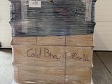 Des cartons de café infusé à froid sont empilés sur des palettes dans un entrepôt