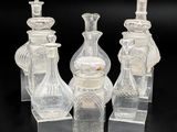 trois vases en verre transparent et un bougeoir posés sur une surface noire