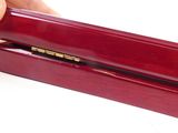 a hand that is holding a wooden box with a pen in it