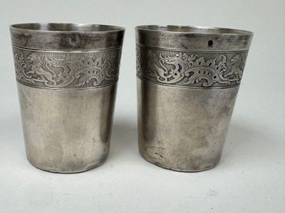 deux tasses en argent posées l'une à côté de l'autre sur une table
