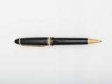 a black and gold ballpoint pen sitting on top of a white surface