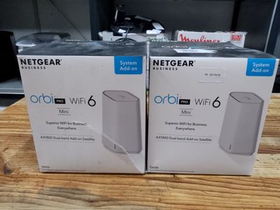 two boxes of netgear orb wifi router on a wooden table