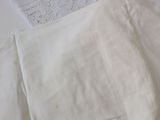 a pile of white linens on a table with a pair of scissors
