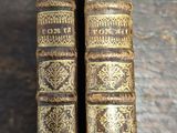two old books sitting on top of a wooden table next to each other