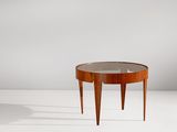 une table ronde avec un plateau en verre, posée sur un meuble blanc