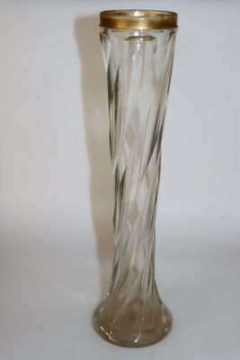 un vase en verre transparent avec un couvercle doré, posé sur une table blanche