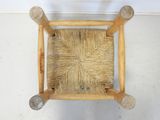 a wooden chair that has a woven seat on it