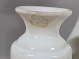 a white vase sitting on a table next to a white vase